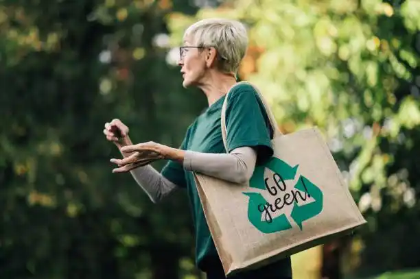 Une personne porte un sac réutilisable marqué « Go green » dans un espace boisé.